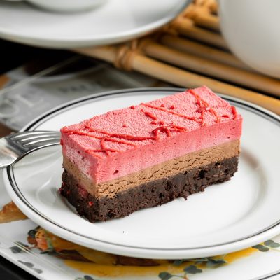chocolate and strawberry cheesecake plate garnished with strawberry syrup
